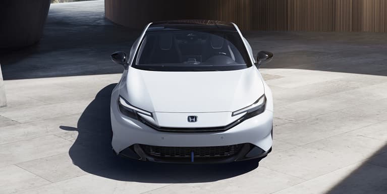 2027 Honda Prelude in Winter Frost Pearl, front overhead view with modern structure on the background (exhilarating hybrid coupe).
